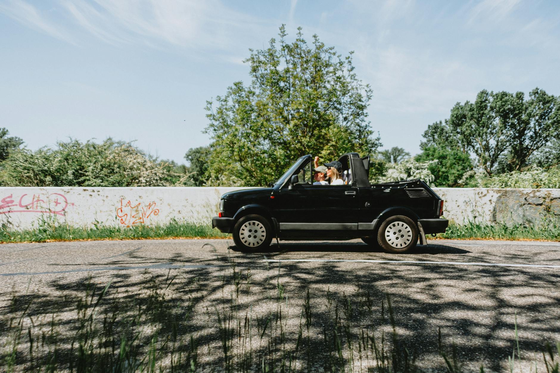 Czarny kabriolet z parą na spokojnej, słonecznej trasie w Czechach