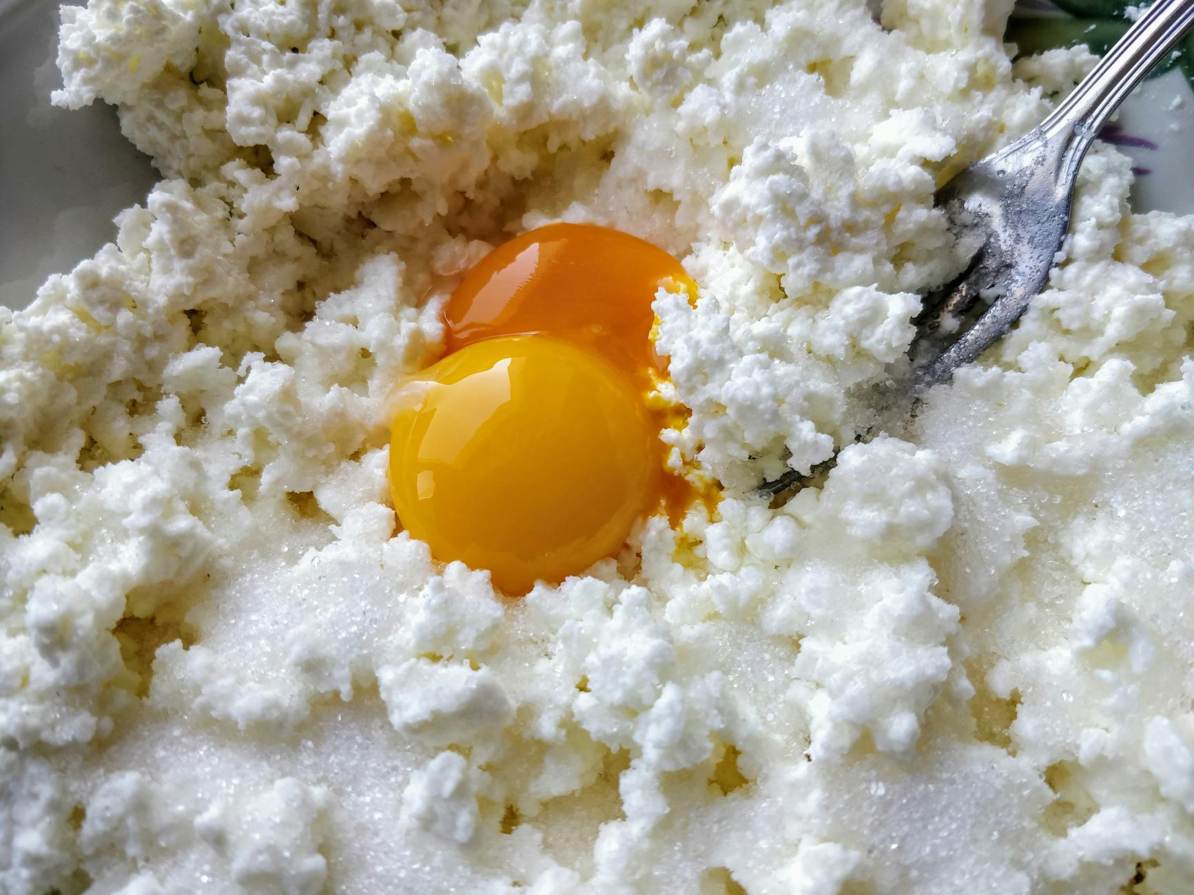 Świeży twaróg wymieszany z żółtkami jaj w misce z bliska