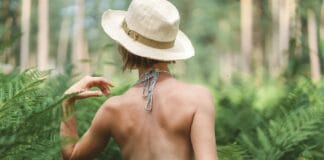Kobieta w kapeluszu spaceruje wśród paproci w lesie